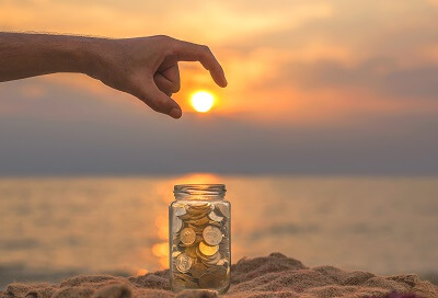 geldanlage im ausland muenzglas vor sonnenuntergang